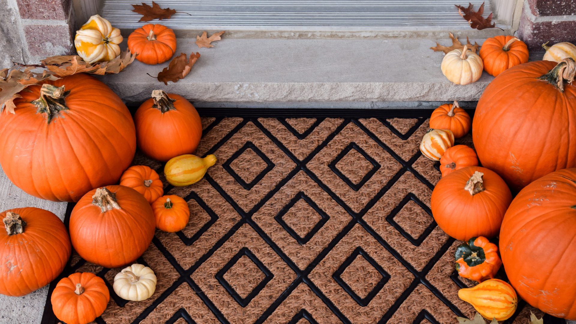 Festive front porch decor with decorative porch mat and various pumpkins